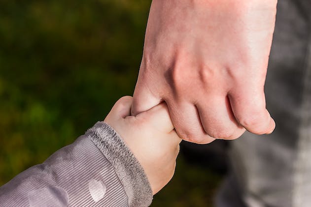 a child holding an adult's finger
