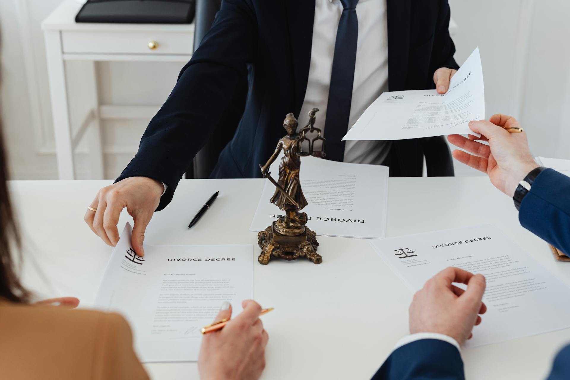 a lawyer sitting across from and exchanging papers with two people