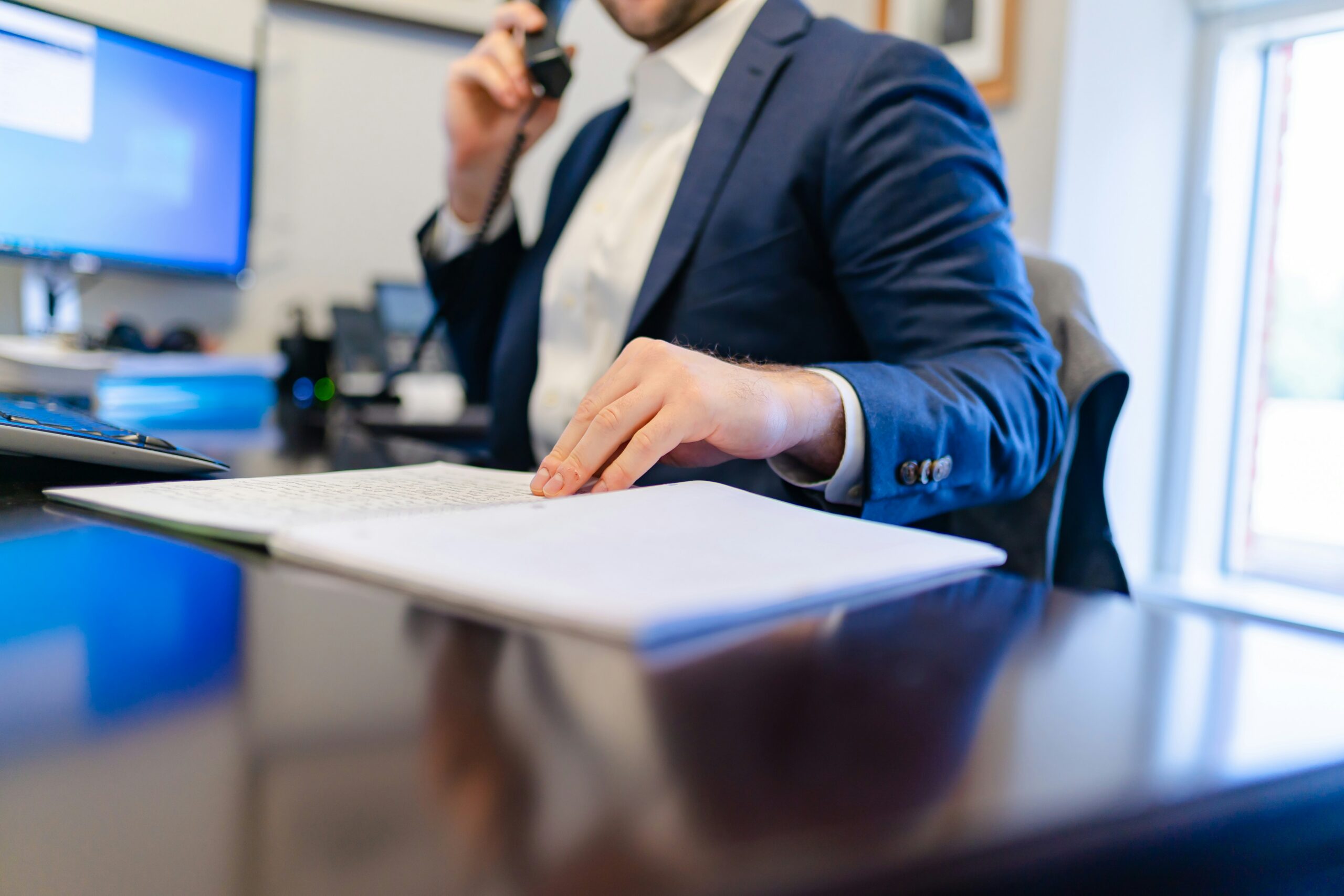 A man in a suit is engaged in a phone conversation, appearing focused and professional. - Pinkham & Associates, APLC A man in a suit is engaged in a phone conversation, appearing focused and professional.